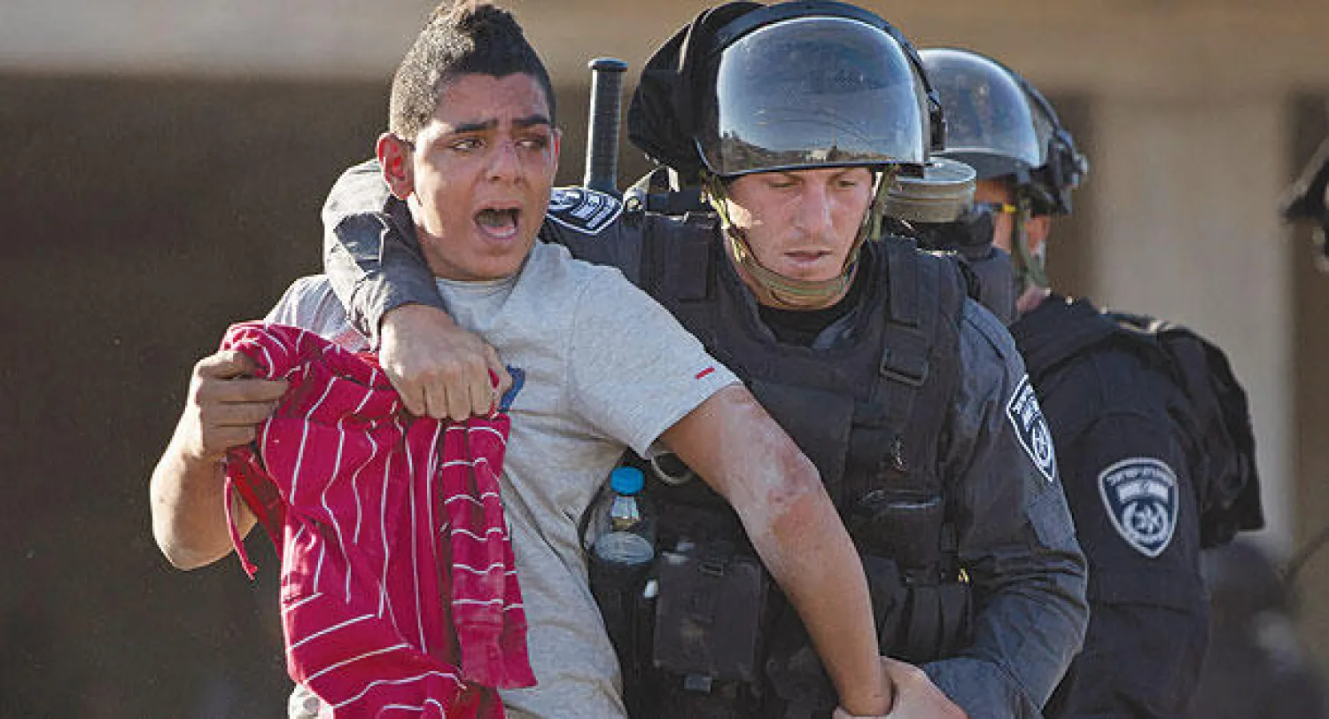 جندي إسرائيلي يعتقل شابا فلسطينيا بعد اشتباكات احتجاجا على مقتل الشاب خير الدين حمدان رميا بالرصاص في قرية كفر كنا بشمال إسرائيل أمس (أ.ب)