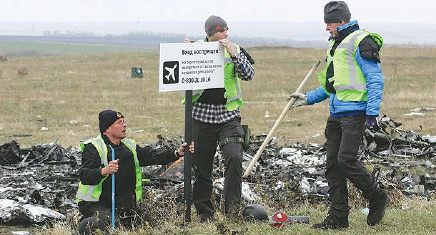 خبراء أوكرانيون يضعون إشارة «ممنوع الاقتراب» أمام حطام للطائرة الماليزية المحطمة في دونيتسك بشرق أوكرانيا أمس (إ.ب.أ)
