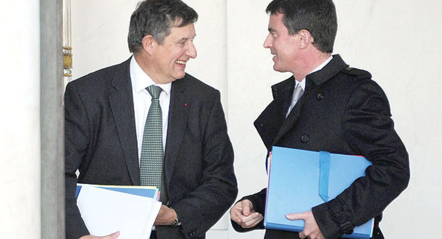 رئيس الوزراء الفرنسي مانويل فالس (يمين) يتحدث إلى الأمين العام لقصر الرئاسة جان بيار جوييه  لال الاجتماع الحكومي في الإليزيه أمس (أ.ف.ب)