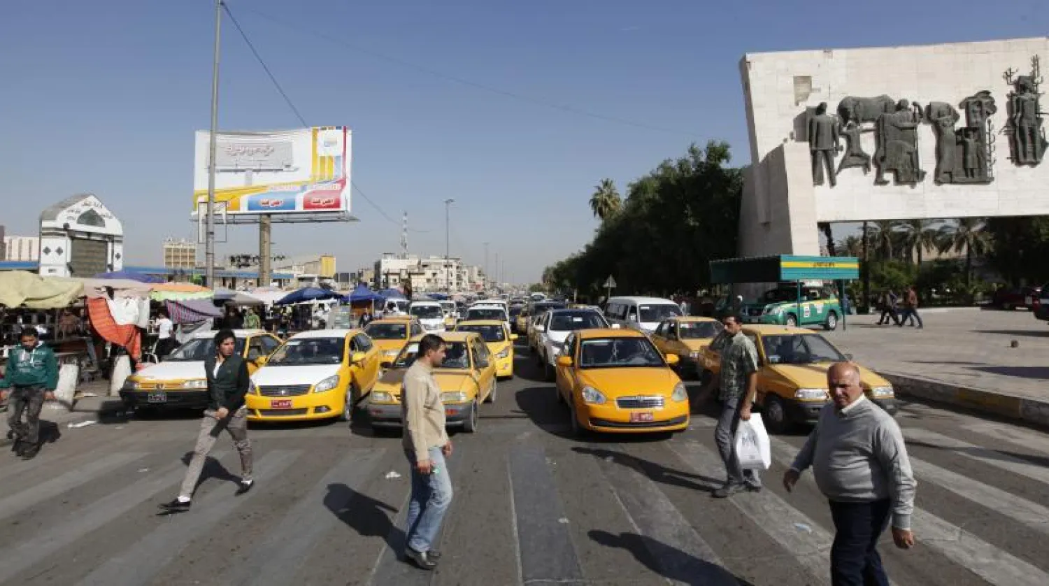 عراقيون يعبرون الشارع في ساحة التحرير قرب نصب الحرية وسط بغداد  (رويترز)