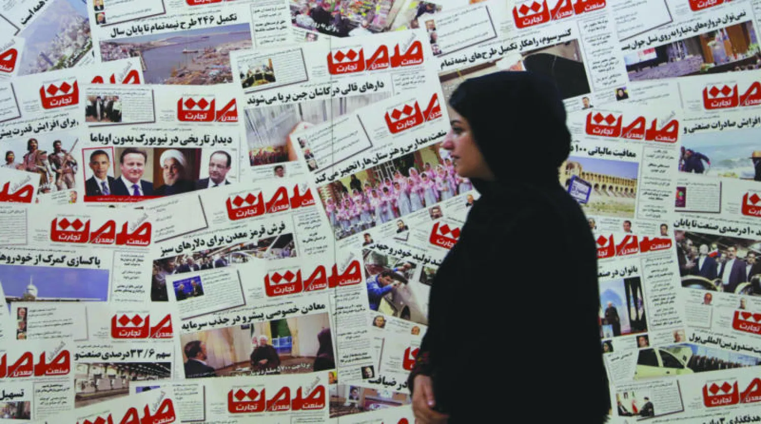 إيرانية تمر من أمام حائط مليء بصور للصفحة الاولى لأحدى الصحف الإيرانية بمناسبة المعرض السنوي للصحافة الإيرانية (أ.ف.ب)