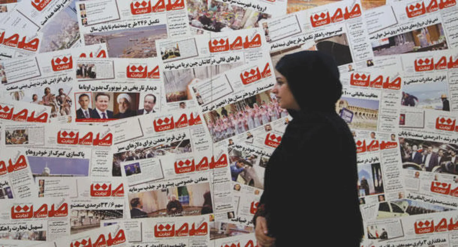 إيرانية تمر من أمام حائط مليء بصور للصفحة الاولى لأحدى الصحف الإيرانية بمناسبة المعرض السنوي للصحافة الإيرانية (أ.ف.ب)