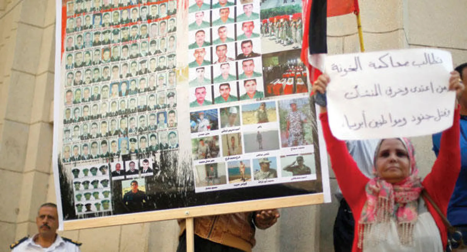 متظاهرة مصرية تقف أمام ملصق عليه وجوه لبعض الجنود ورجال الشرطة الذين قتلوا على يد مسلحين متطرفين، خلال مسيرة مناهضة للعنف والإرهاب بوسط القاهرة (رويترز)