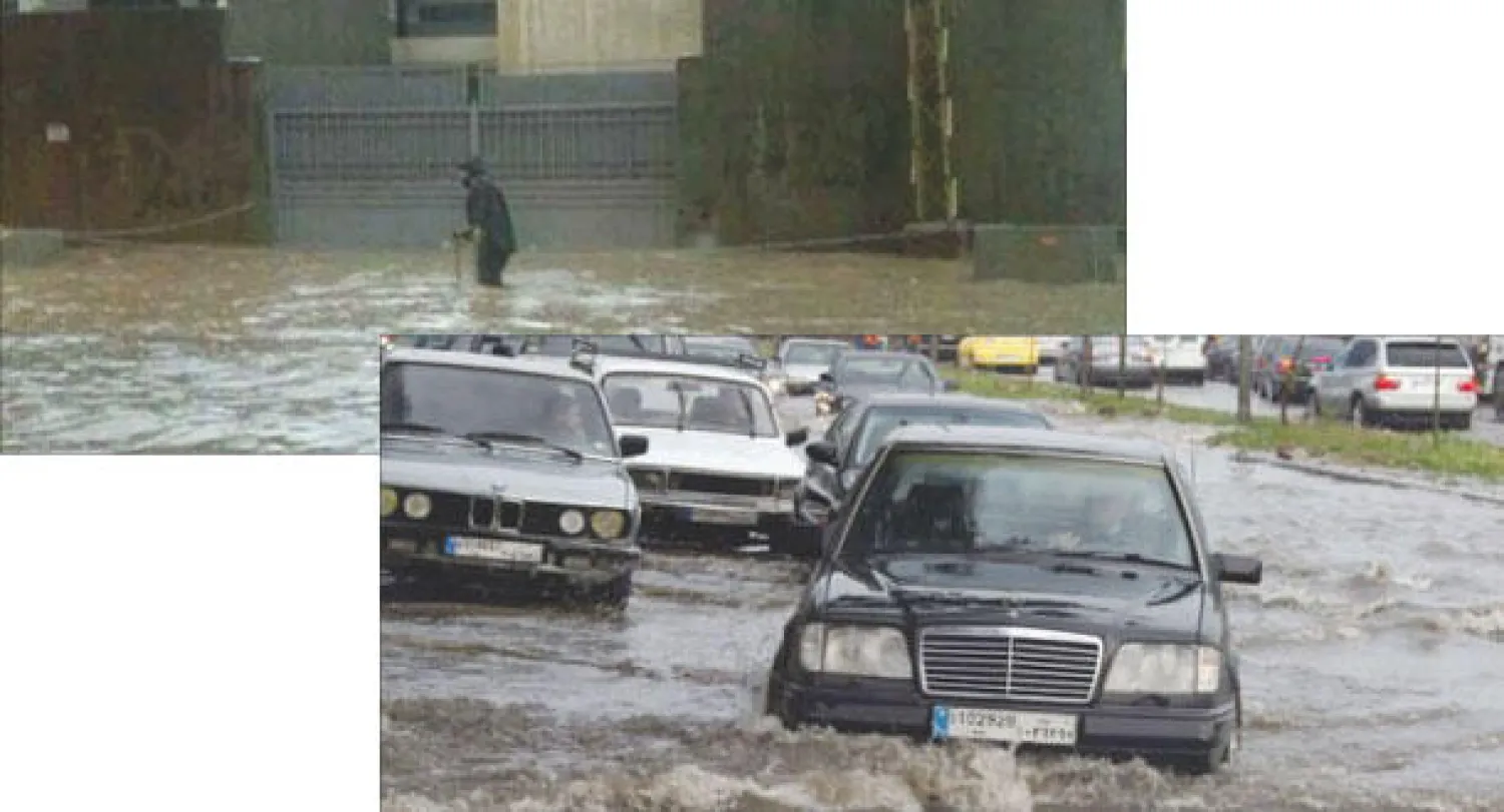 طرقات بيروت تتحول إلى بحيرات إثر هطول الأمطار، لبناني يحاول اجتياز الطريق المقطوع بمياه الشتاء.