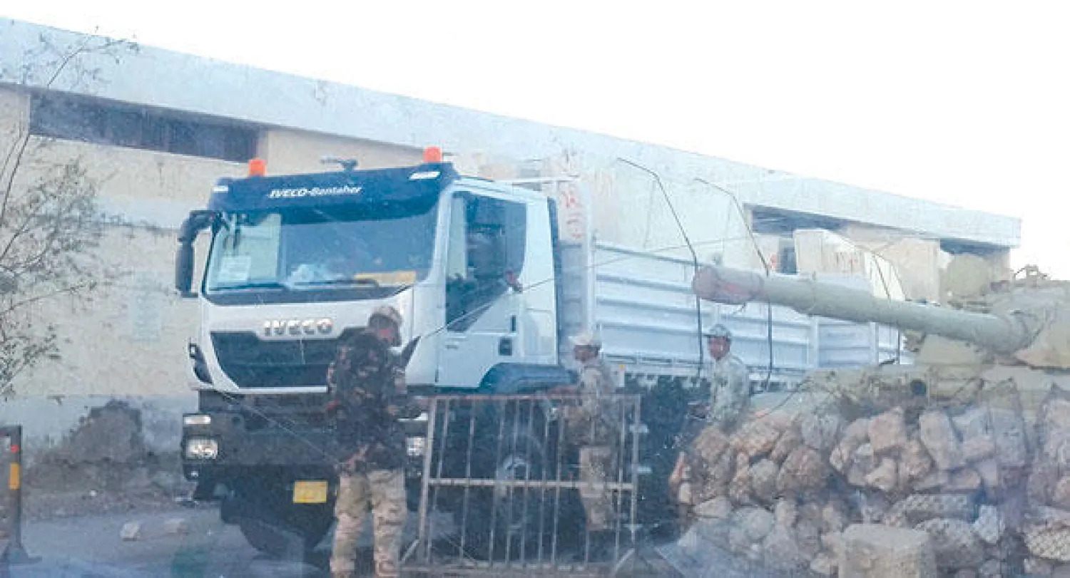 جنود على الحدود المصرية ــ الليبية يقفون خلف متاريس وبجوار دبابة، ويفحصون أوراق إحدى سيارات نقل البضائع قبل السماح لها بالدخول («الشرق الأوسط»)