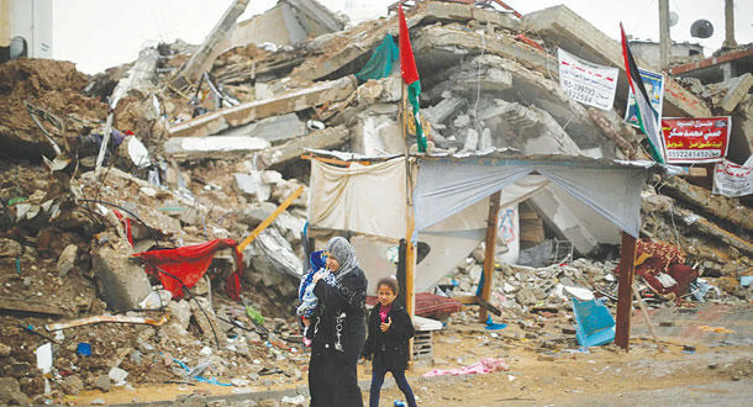 عائلة فلسطينية تمر من امام ركام احد المباني التي دمرتها المقاتلات الاسرائيلية خلال الحرب الاخيرة على غزة (رويترز)