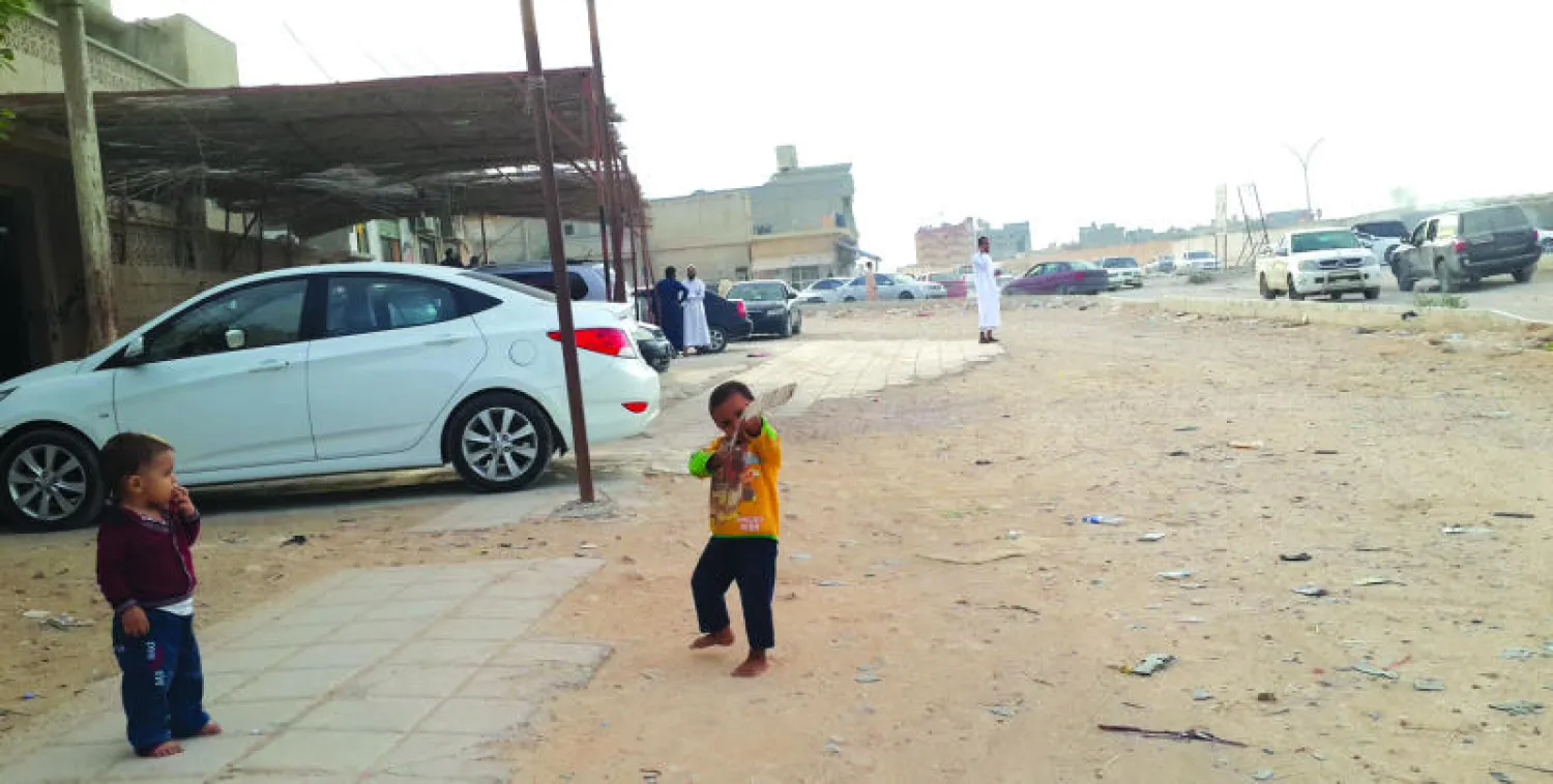 طفل ليبي يقف على جانب شارع الحرية في مدينة طبرق ويبدو متأثرا بأجواء الحرب التي تشهدها البلاد، حيث يصوب بعصا كأنها بندقية، وأحد أقرانه يراقب حركته (تصوير: «الشرق الأوسط»)