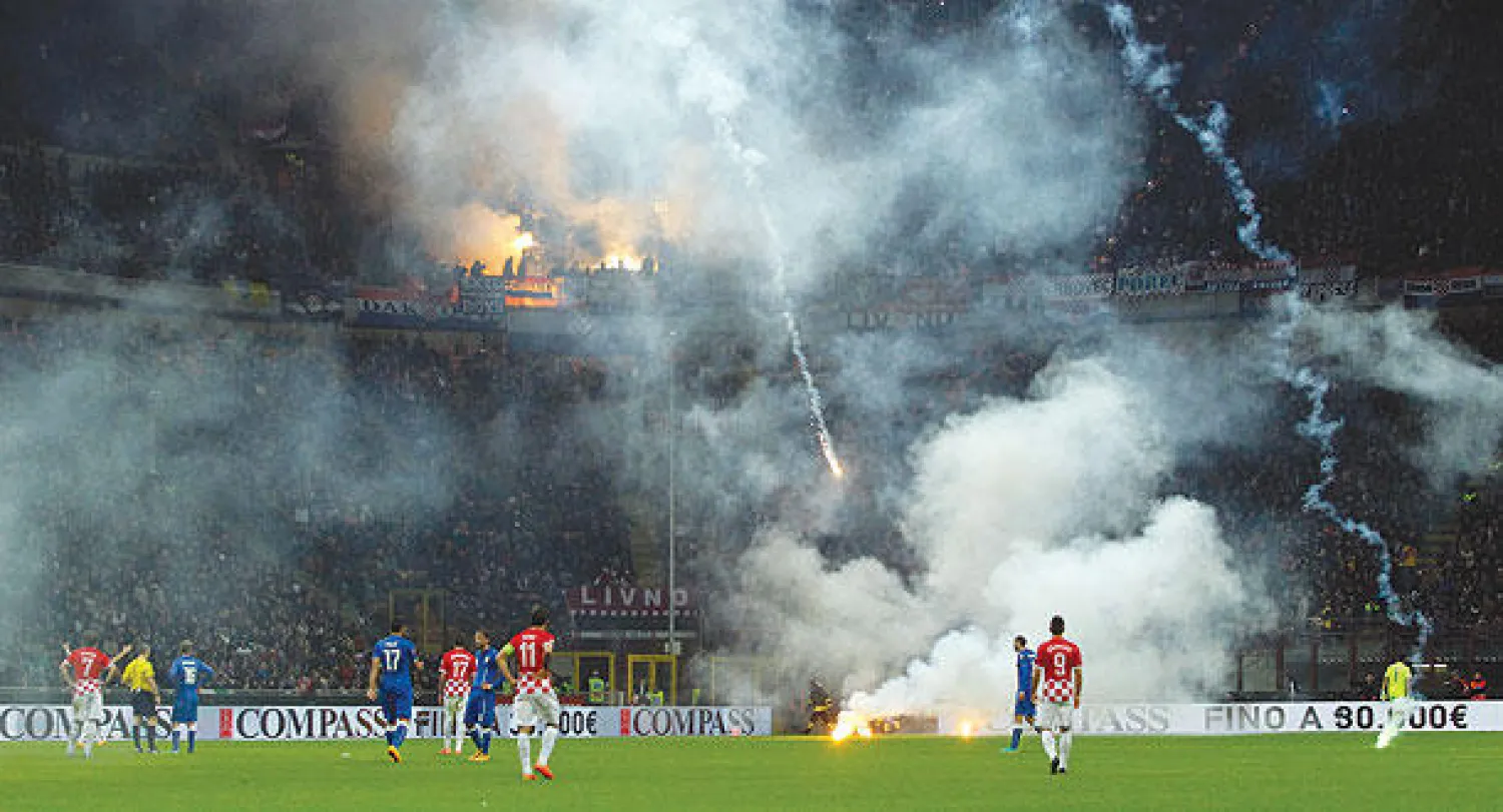 الألعاب النارية تمطر على أرضية ملعب سان سيرو خلال مباراة إيطاليا وكرواتيا (رويترز)