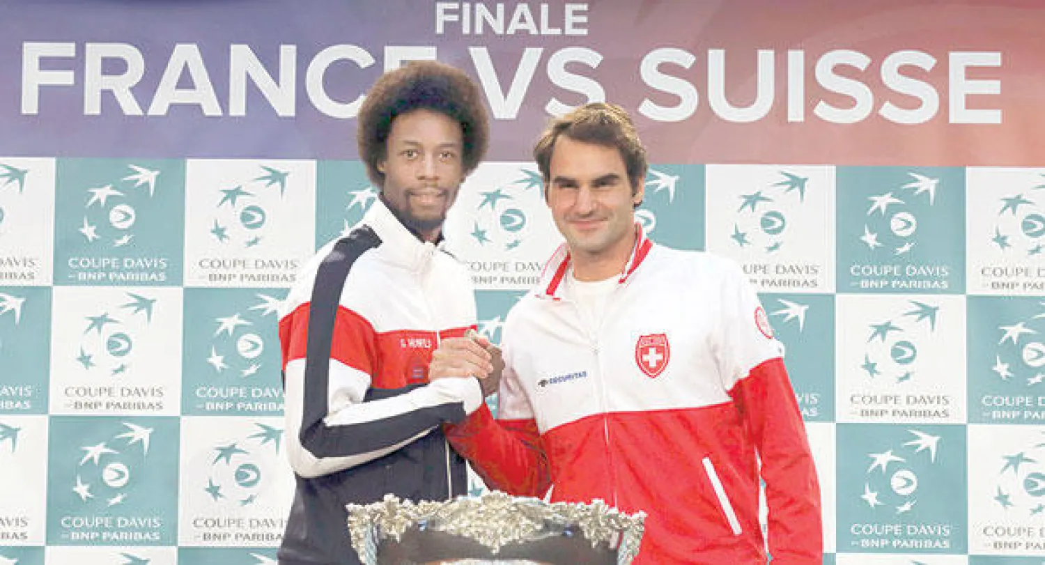 فيدرر يصافح الفرنسي مونفيس الذي سيلتقيه  في الجولة الأولى لكأس ديفيز (رويترز)