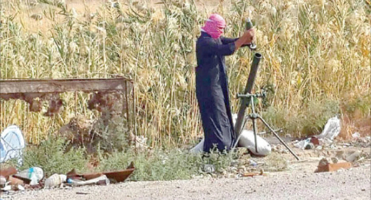 عنصر في «داعش» يهم بإطلاق قذيفة هاون خلال معارك مع القوات العراقية في الرمادي أمس (أ.ب)
