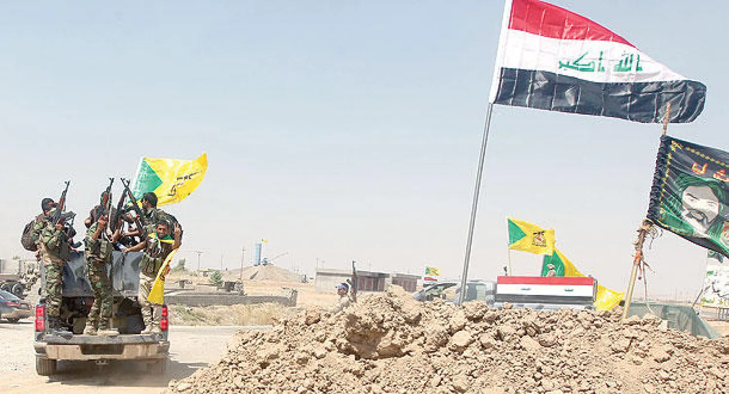رايات حسينية مرفوعة فوق موقع وسيارة عسكرية إلى جانب العلم العراقي في الطريق بين آمرلي وتكريت (أ.ف.ب)
