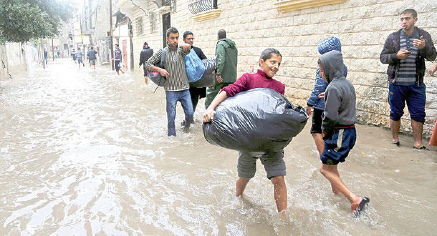 سكان من غزة يغادرون منازلهم التي تعرضت لأضرار كبيرة بسبب الأمطار الغزيرة  التي سقطت على المدينة خلال الأيام الأخيرة (أ.ب)