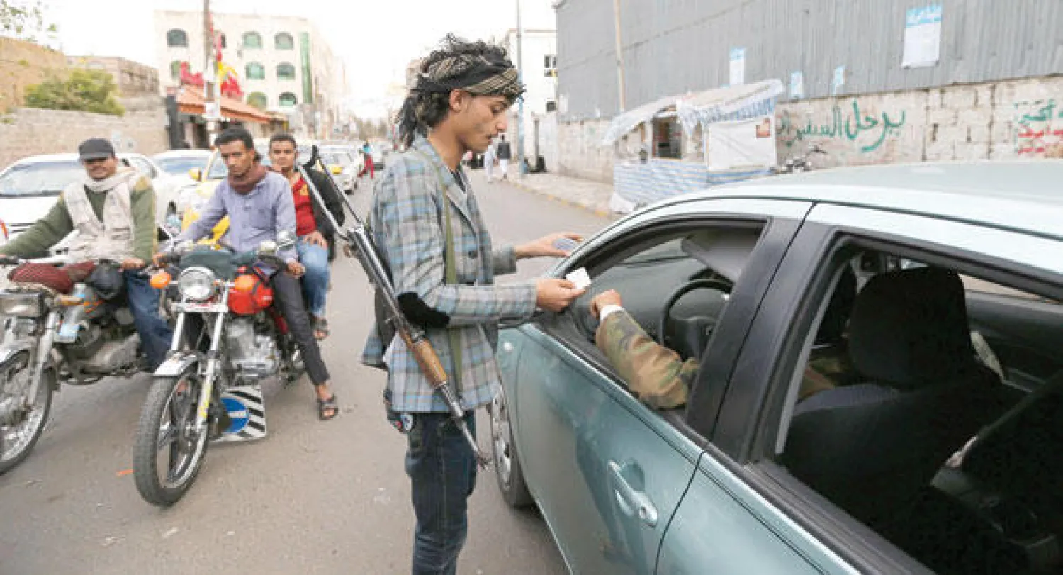 أحد عناصر الحوثيين يتفحص أوراقا ثبوتية لسائق سيارة في نقطة تفتيش بصنعاء أمس (رويترز)