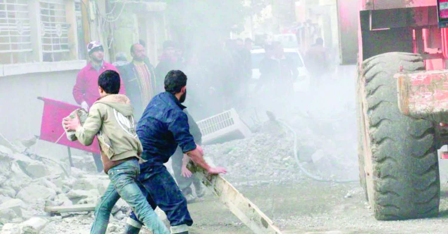 رجال من مدينة الرقة يتعاملون مع الدمار الذي سببه قصف طيران النظام أحد المباني (رويترز)