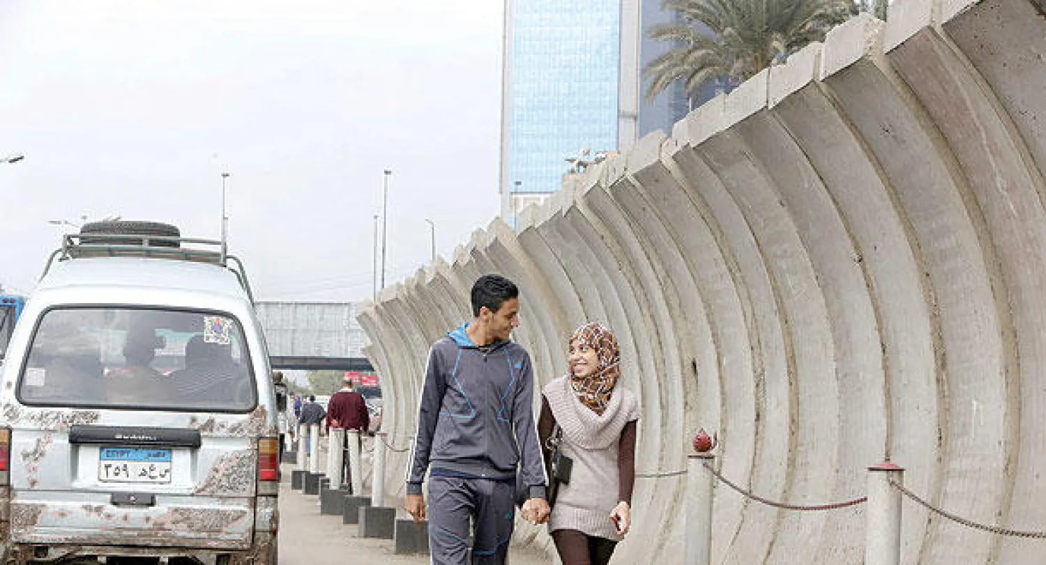 مصريان يمشيان بجانب  حاجز خرساني يحيط بوزارة الخارجية في القاهرة أمس (أ.ف.ب)