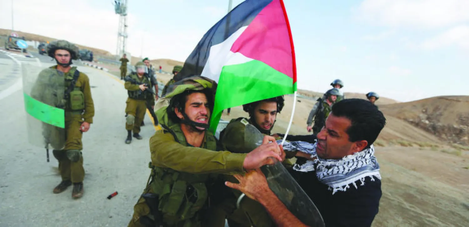 شرطي إسرائيلي يعنف شابا فلسطينيا خلال المواجهات التي حدثت بين قوات إسرائيلية وعدد من الفلسطينيين بالقرب من الضفة الغربية أمس (رويترز)