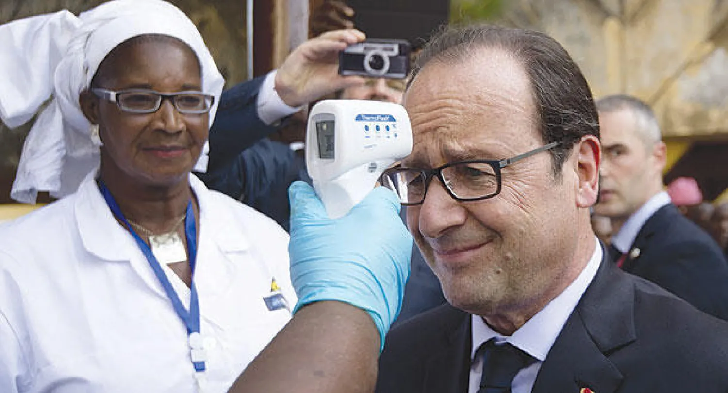 هولاند يخضع لقياس درجة حرارته أثناء وصوله لمستشفى في كوناكري أمس في إطار زيارته التضامنية مع غينيا لمواجهة إيبولا (أ.ف.ب)