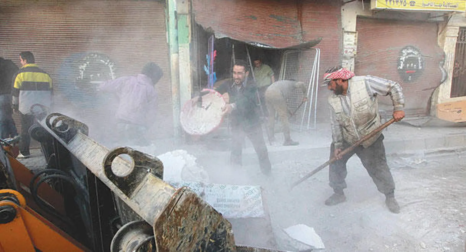 سوريون يحاولون إزالة الركام بعد 4 غارات للنظام على احدى مناطق الرقة أمس (رويترز)