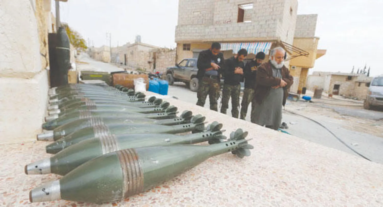 مقاتلون في الجيش الحر يصلّون بالقرب من قذائف مورتر على جبهة حندرات، قرب حلب (رويترز)