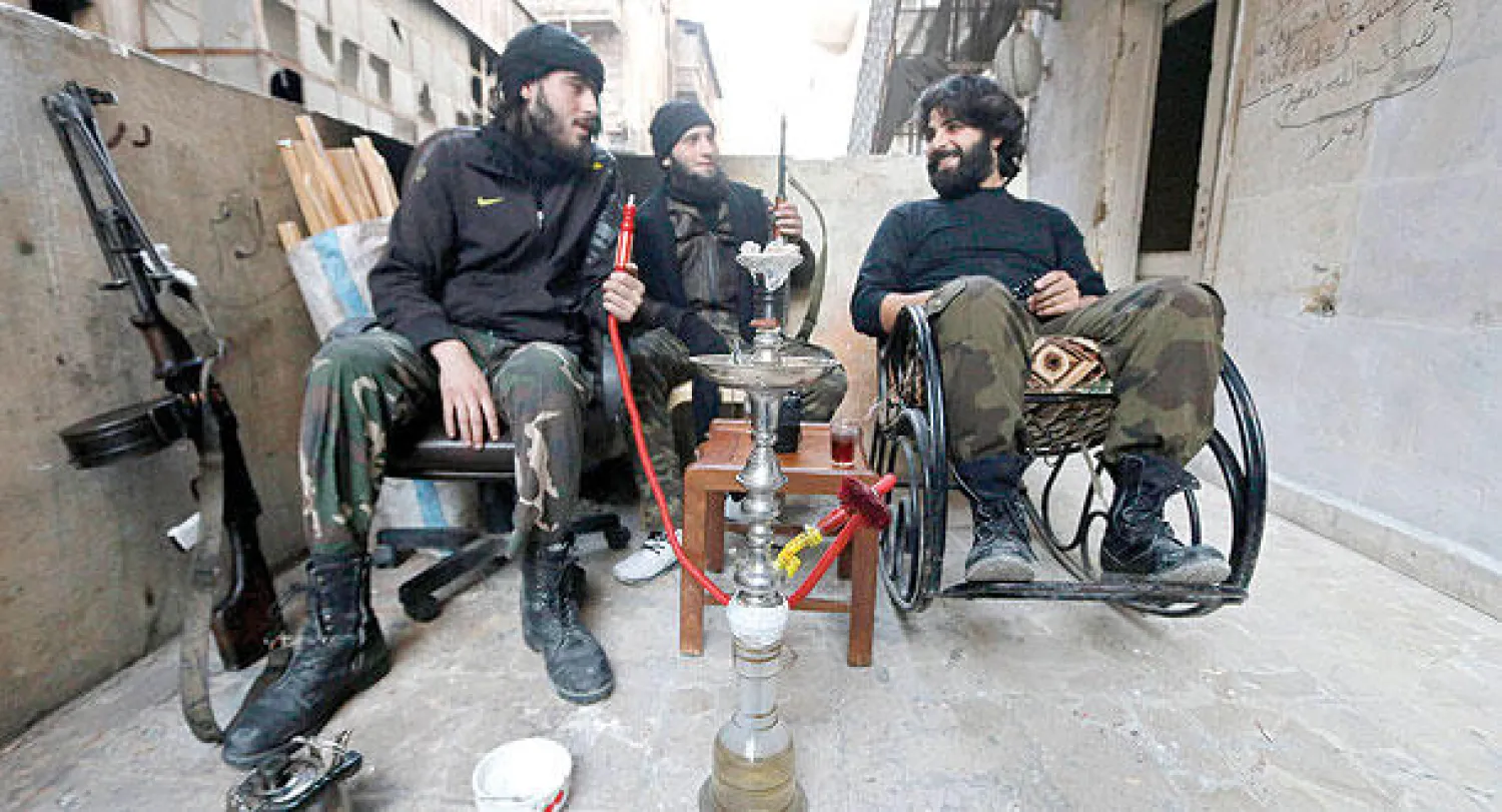 مقاتلون من «جيش المجاهدين» المحسوب على الجيش السوري الحر في استراحة عند حاجز زينو بحلب (رويترز)