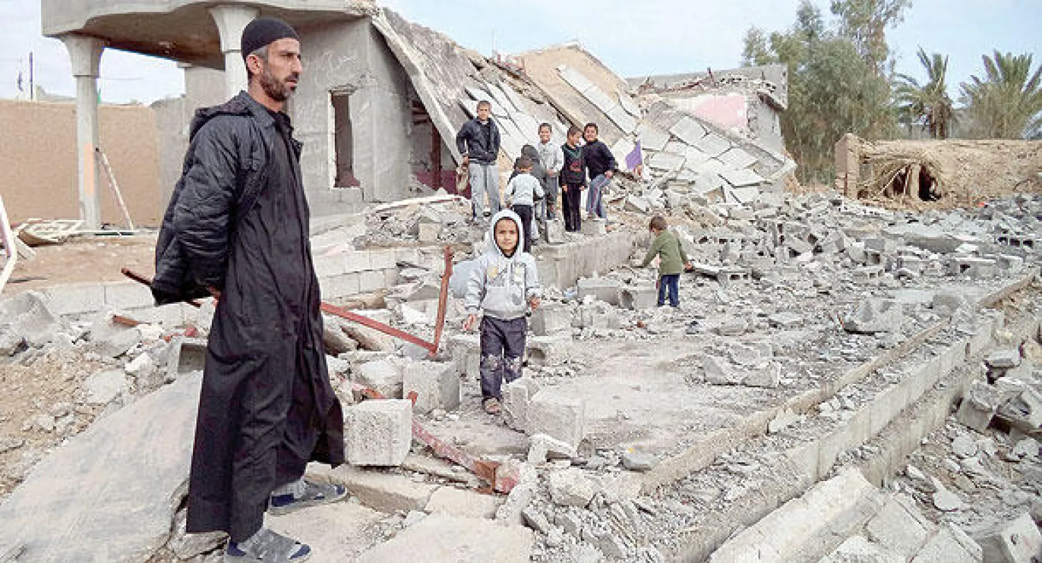 عراقيون وسط أنقاض حسينية دمرت خلال مواجهات بين قوات الأمن و«داعش» في قرناس إلى الشرق من تكريت أمس (إ.ب.أ)