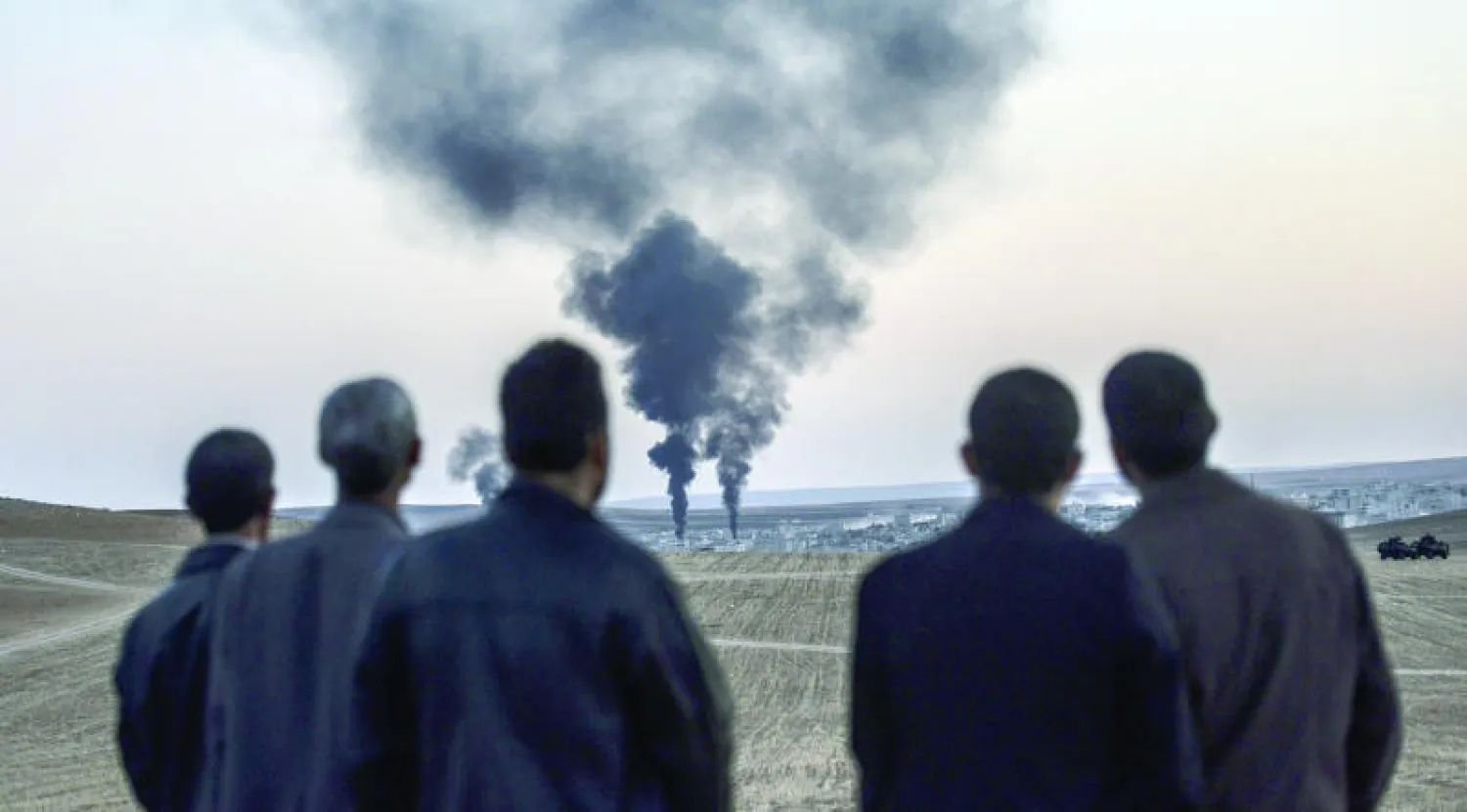 سكان محليون يتابعون الدخان المنبعث من كوباني (عين العرب) السورية التي يشن التحالف الدولي غارات عليها لاستهداف «داعش» رغم امتداده في شمال وسوريا وشرقها (إ.ف.ب)
