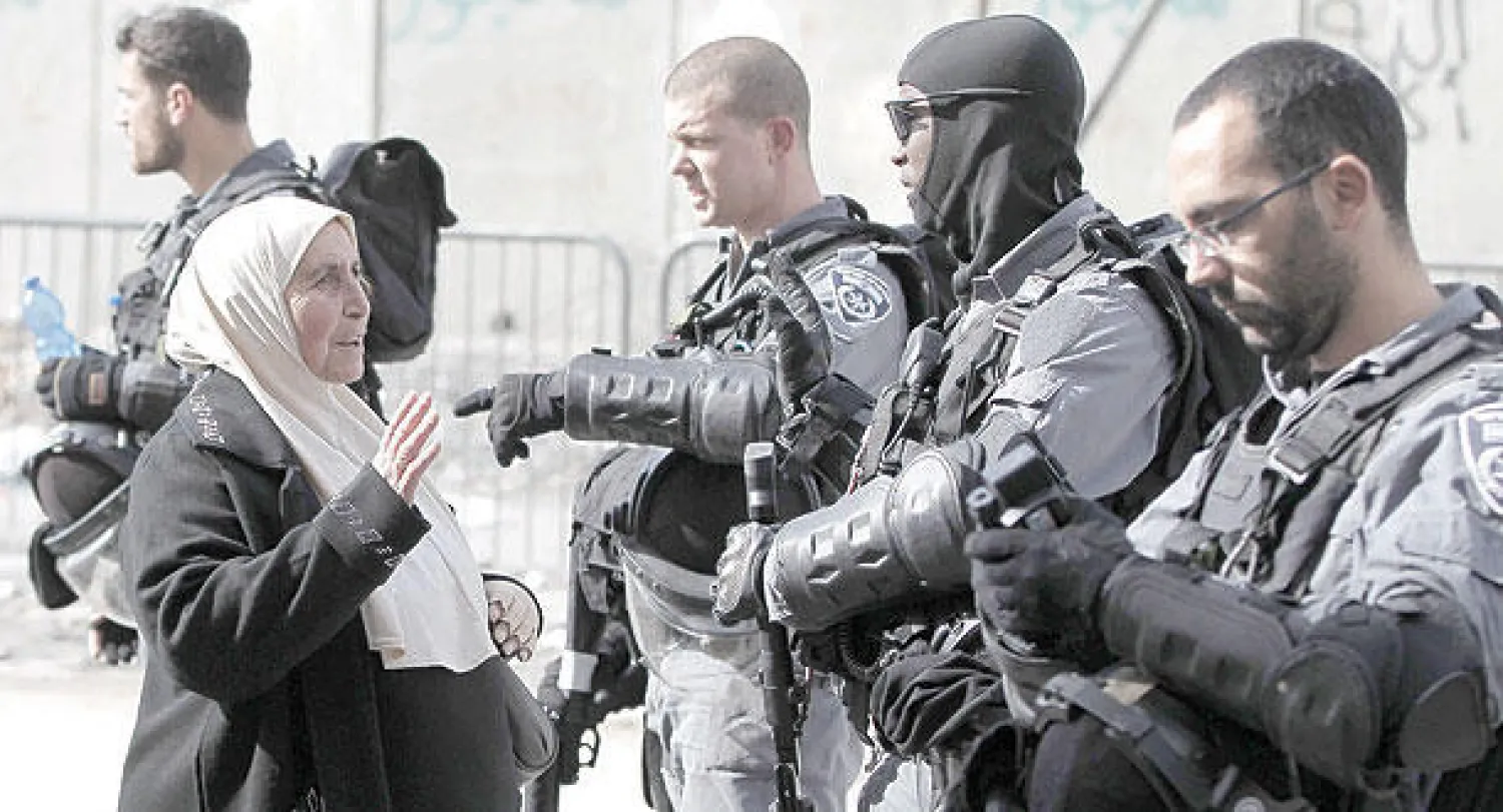 فلسطينية تجادل أفرادا من قوات الأمن الإسرائيلية أثناء تدمير قوات الاحتلال متجرا يملكه فلسطيني في مخيم الشويفات بالقدس أمس (أ.ف.ب)