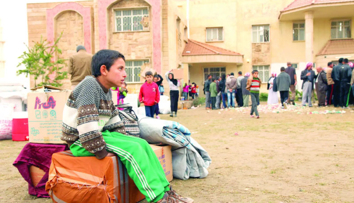 صبي نازح من محافظة نينوى يجلس في باحة مدرسة في دهوك تحولت إلى مخيم للنازحين (رويترز)