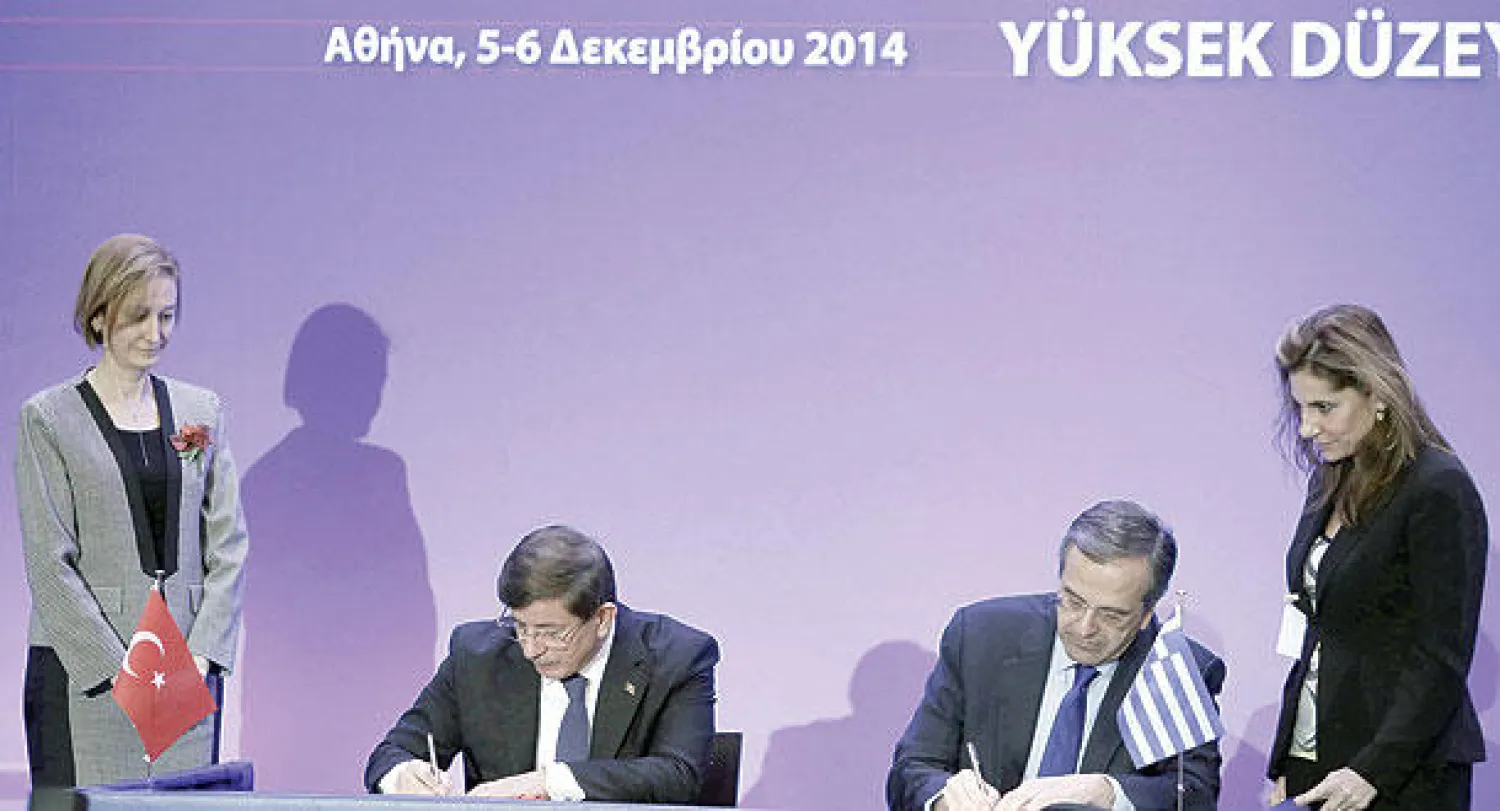 رئيس الوزراء اليوناني أنطونيوس ساماراس يوقع مع نظيره التركي أحمد داوود أوغلو اتفاقية خلال زيارته لأثينا أمس (إ. ب.أ)