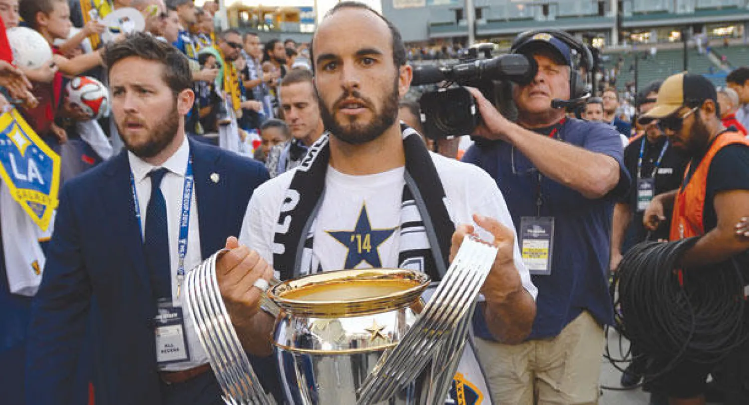 دونوفان أسطورة الكرة الأميركية يحمل كأس الدوري في آخر ظهور له قبل الاعتزال (أ.ف.ب)