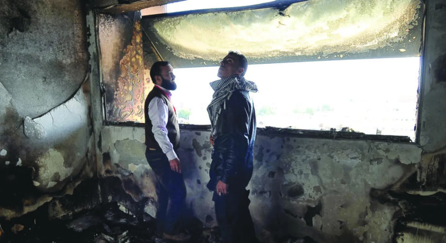 عاملان في المركز الطبي في بنغازي يتفقدان الخسائر الناجمة عن قصف تعرض له المبنى امس مما ادى الى اندلاع حريق فيه ( رويترز )