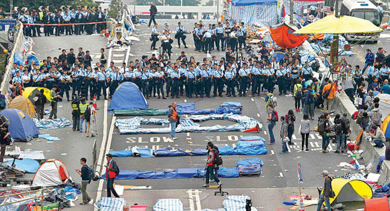 الشرطة أثناء محاولتها تفكيك آخر مواقع المتظاهرين  في حي أدميرالتي القريب من مقر الحكومة في هونغ كونغ أمس (رويترز)