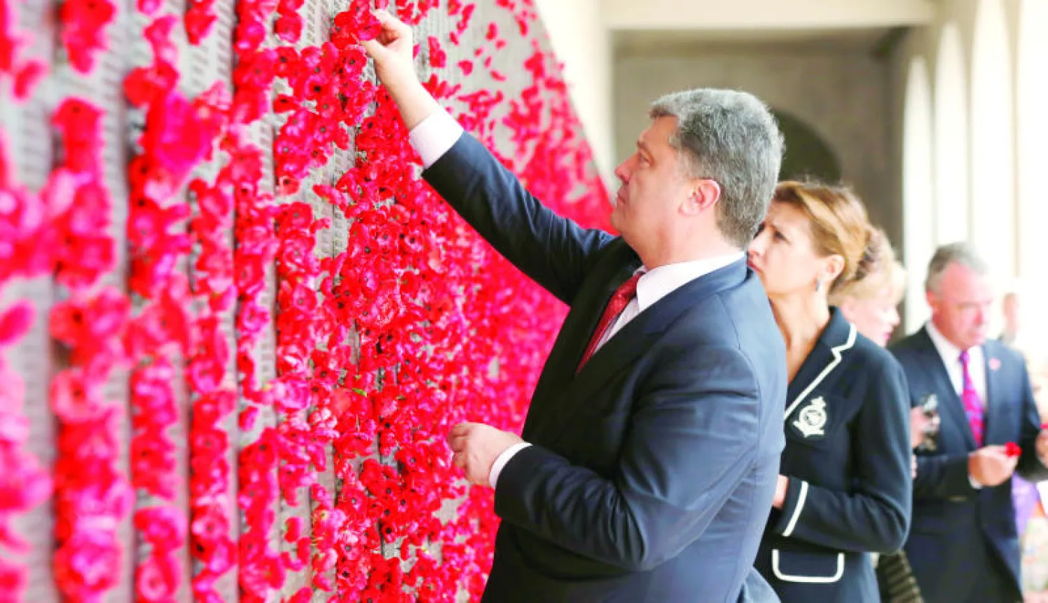 بوروشينكو يضع نباتات خشخاش على جدار خلال زيارته للنصب التذكاري للحرب الأسترالية بالعاصمة كانبيرا أمس، وتبدو إلى جانبه زوجته (ا.ب)