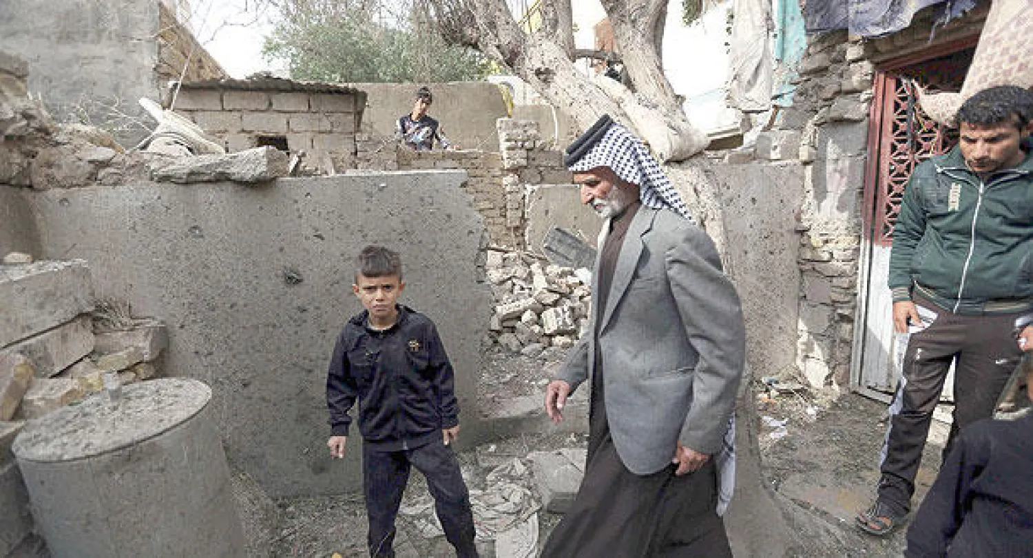 عراقيون يعاينون آثار قذائف هاون سقطت في كربلاء مساء أول من أمس (أ.ب)