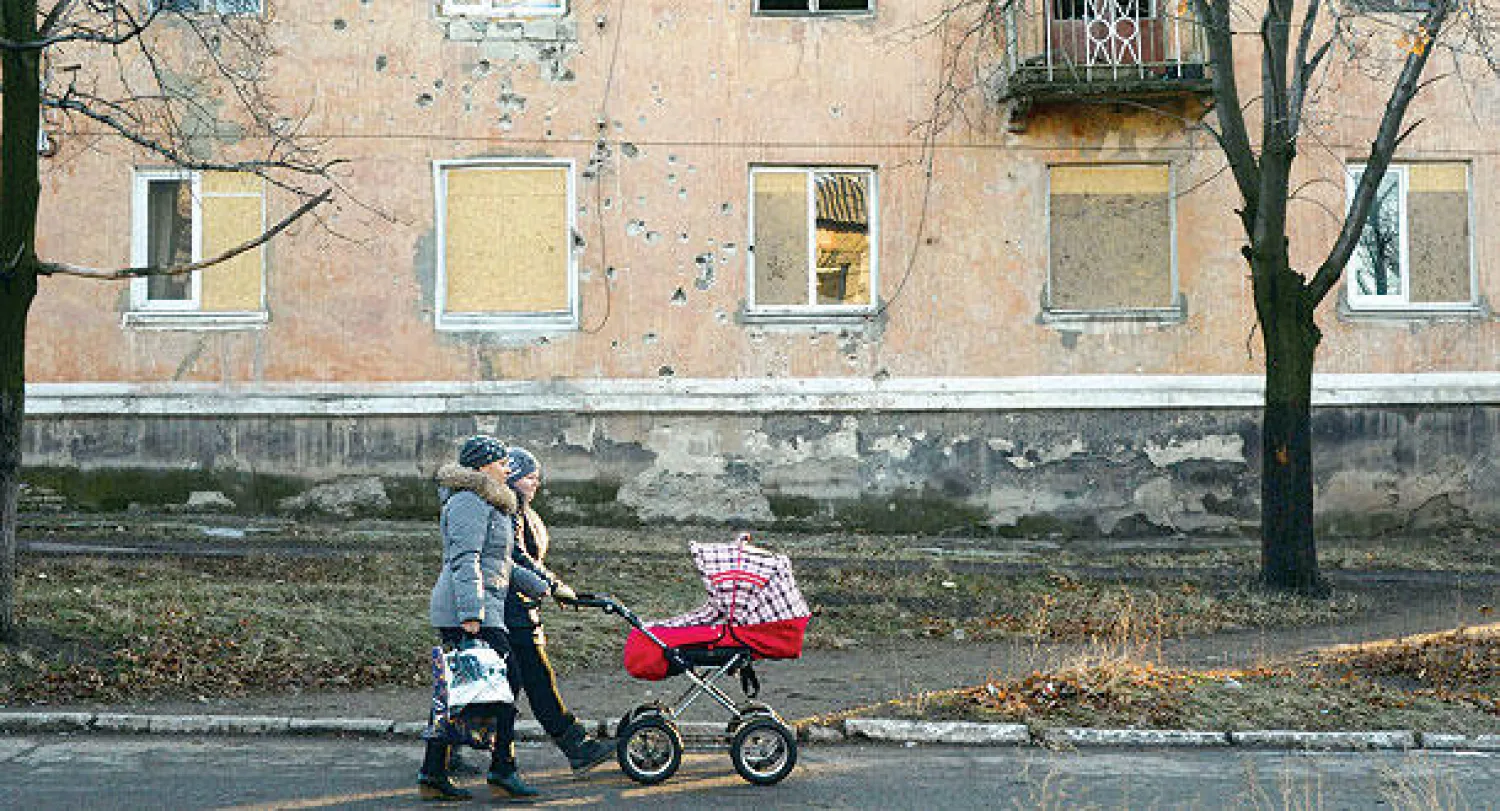 امرأتان تمران أمام مبان مدمرة في بلدة كومينار قرب منطقة دونيتسك في شرق أوكرانيا أمس (أ.ف.ب)