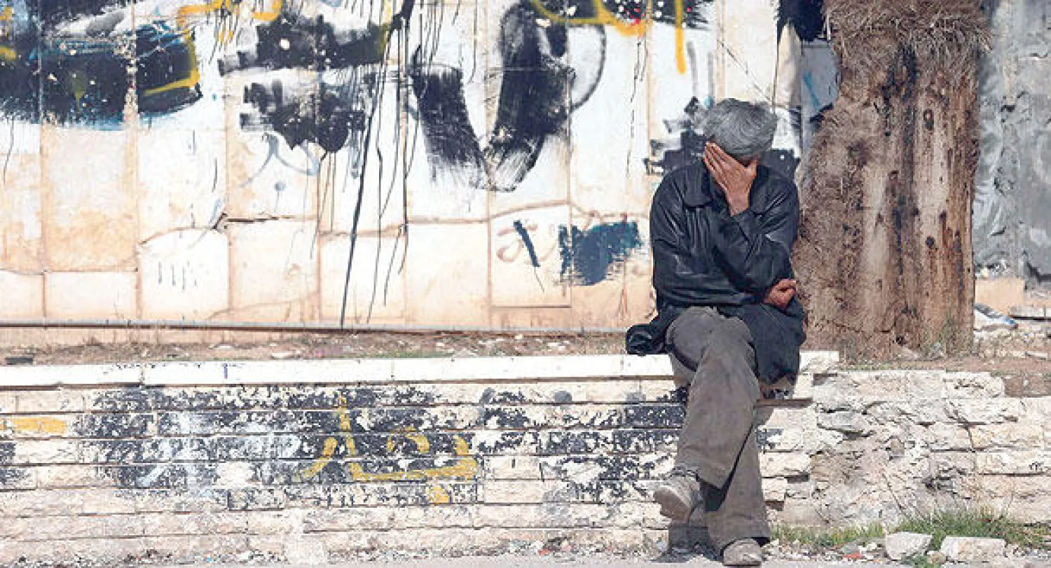 سوري يجلس متأثرا بالدمار الذي لحق بالمباني في الغوطة الشرقية قرب دمشق (رويترز)