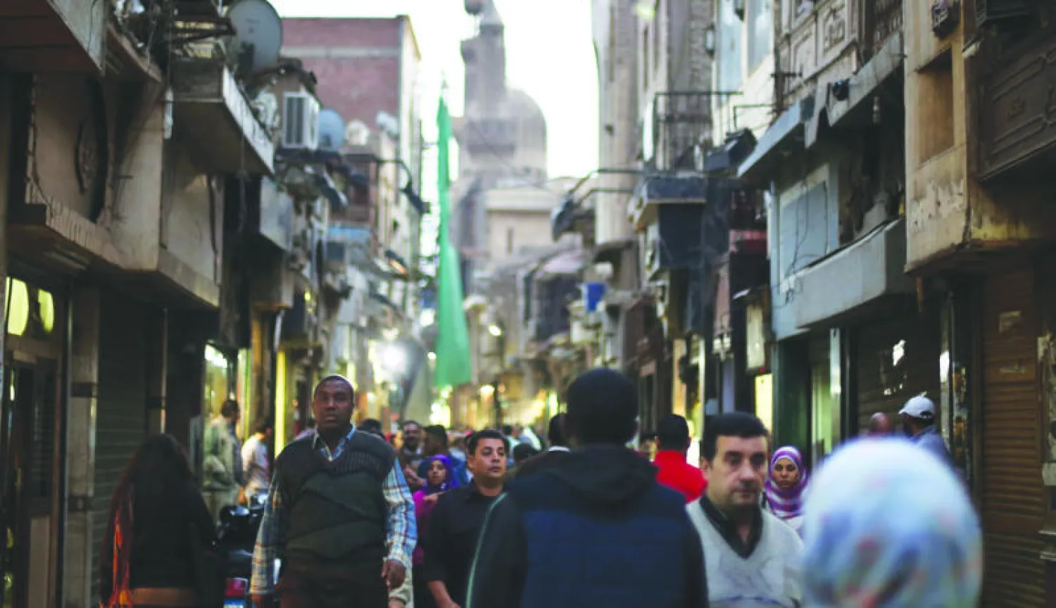 مواطنون مصريون في حياتهم اليومية في شارع المعز لدين الله في القاهرة القديمة أمس (أ.ف.ب)
