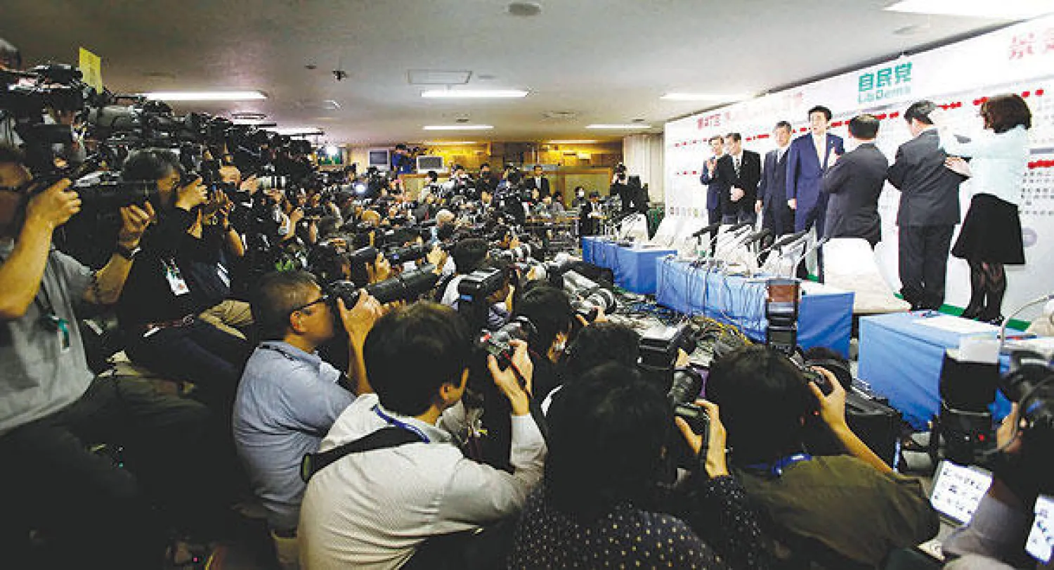 مصورون يلتقطون صورا لرئيس الوزراء الياباني شينزو آبي في مقر حزبه بطوكيو أمس (رويترز)