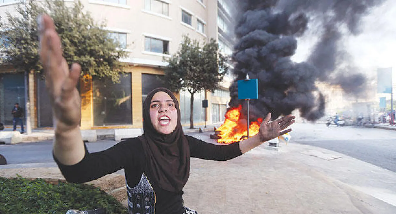 وضحة السيد زوجة العسكري المخطوف خالد مقبل أمام إطارات محروقة أشعلها أهالي المخطوفين  وسدوا أحد شوارع بيروت أمس للضغط على الحكومة اللبنانية (رويترز)