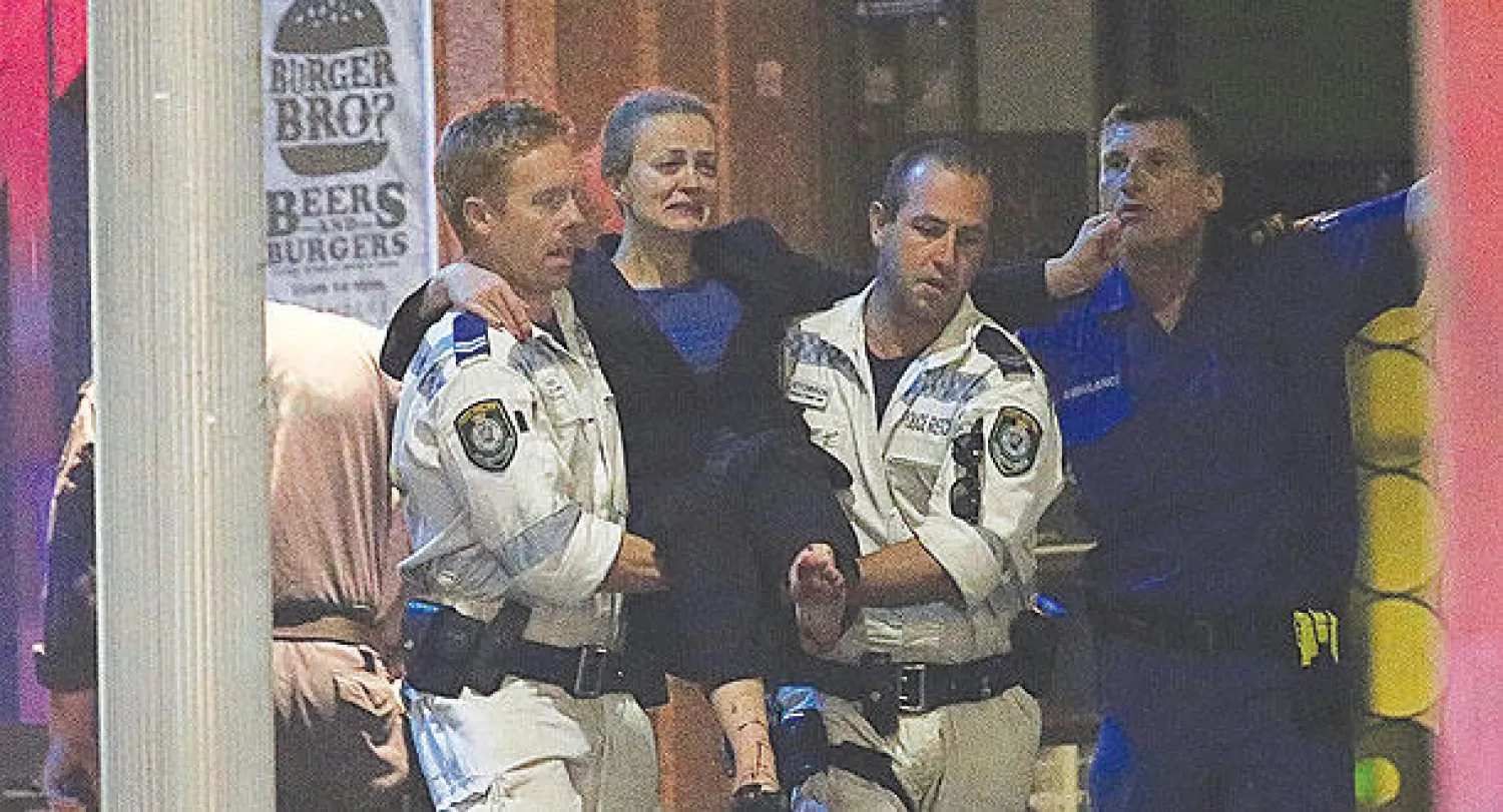 رجلا إسعاف ينقلان رهينة مصابة بعد مداهمة الشرطة لمقهى سيدني (أ.ب) 