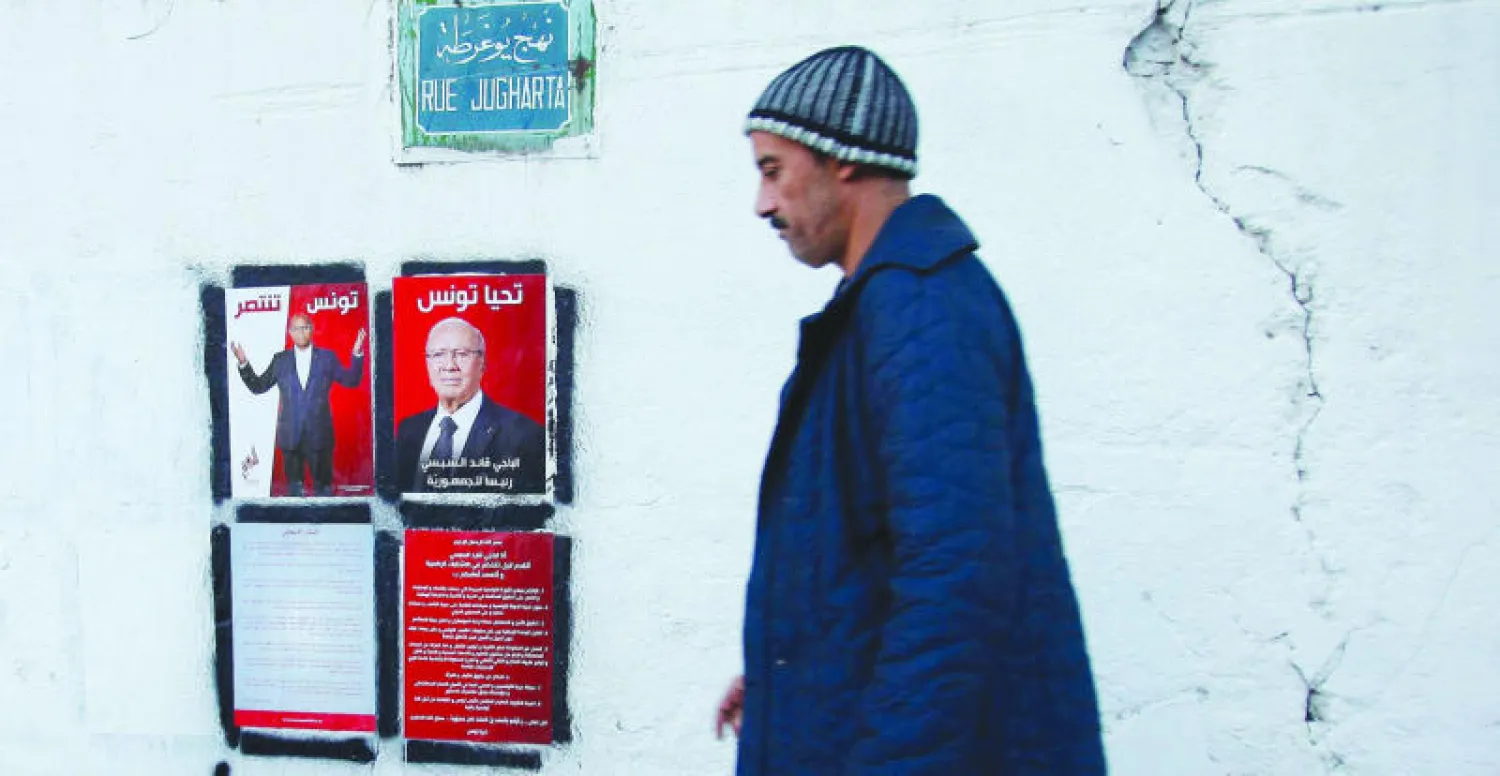 تونسي يمر بجانب صورتين للمرشحين الرئيسيين للانتخابات الرئاسية الباجي قائد السبسي والمنصف المرزوقي (رويترز)