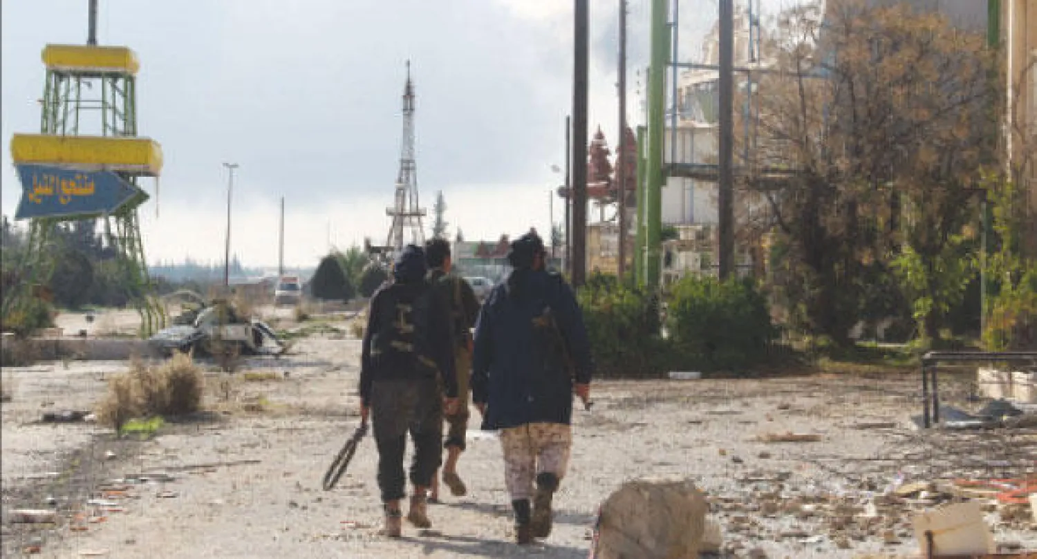 مقاتلون يسيرون باسترخاء في معسكر الحامدية الذي استولت عليه المعارضة أول من أمس هو ومعسكر وادي الضيف في إدلب شمال سوريا (رويترز)