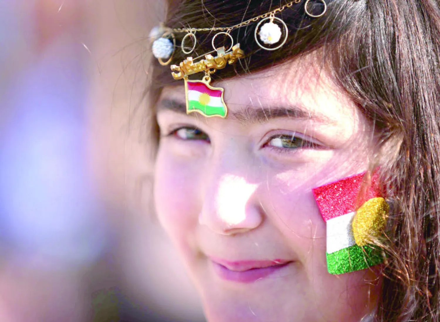 طفلة كردية تبتسم وقد زينت وجهها بعلم كردستان خلال الاحتفالات بـ«يوم العلم» في أربيل أمس (أ.ف.ب)