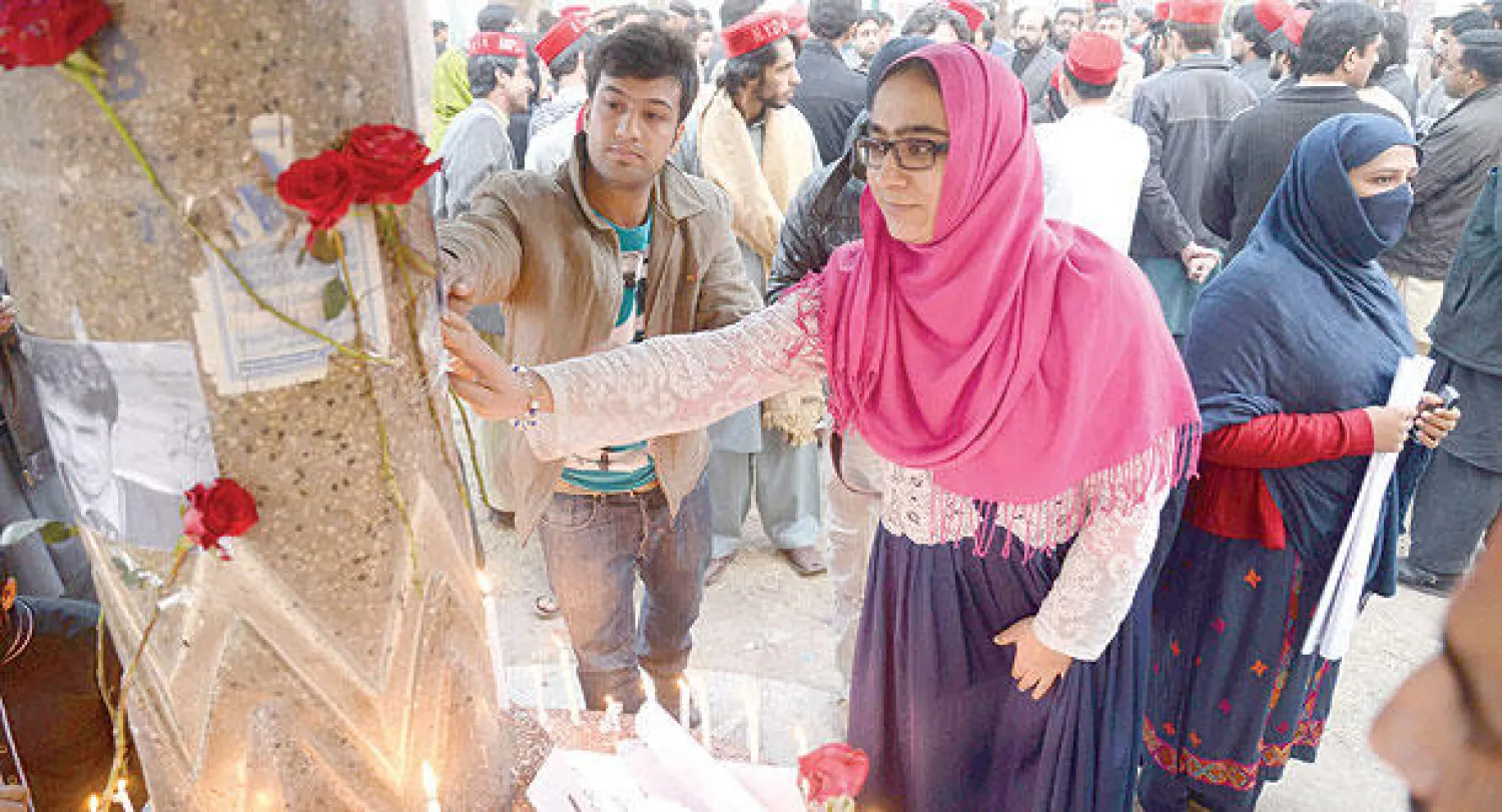 ناشطون من المجتمع المدني الباكستاني يضعون وردا لتذكر ضحايا المجزرة في مدينة بيشاور أمس (أ.ف.ب)