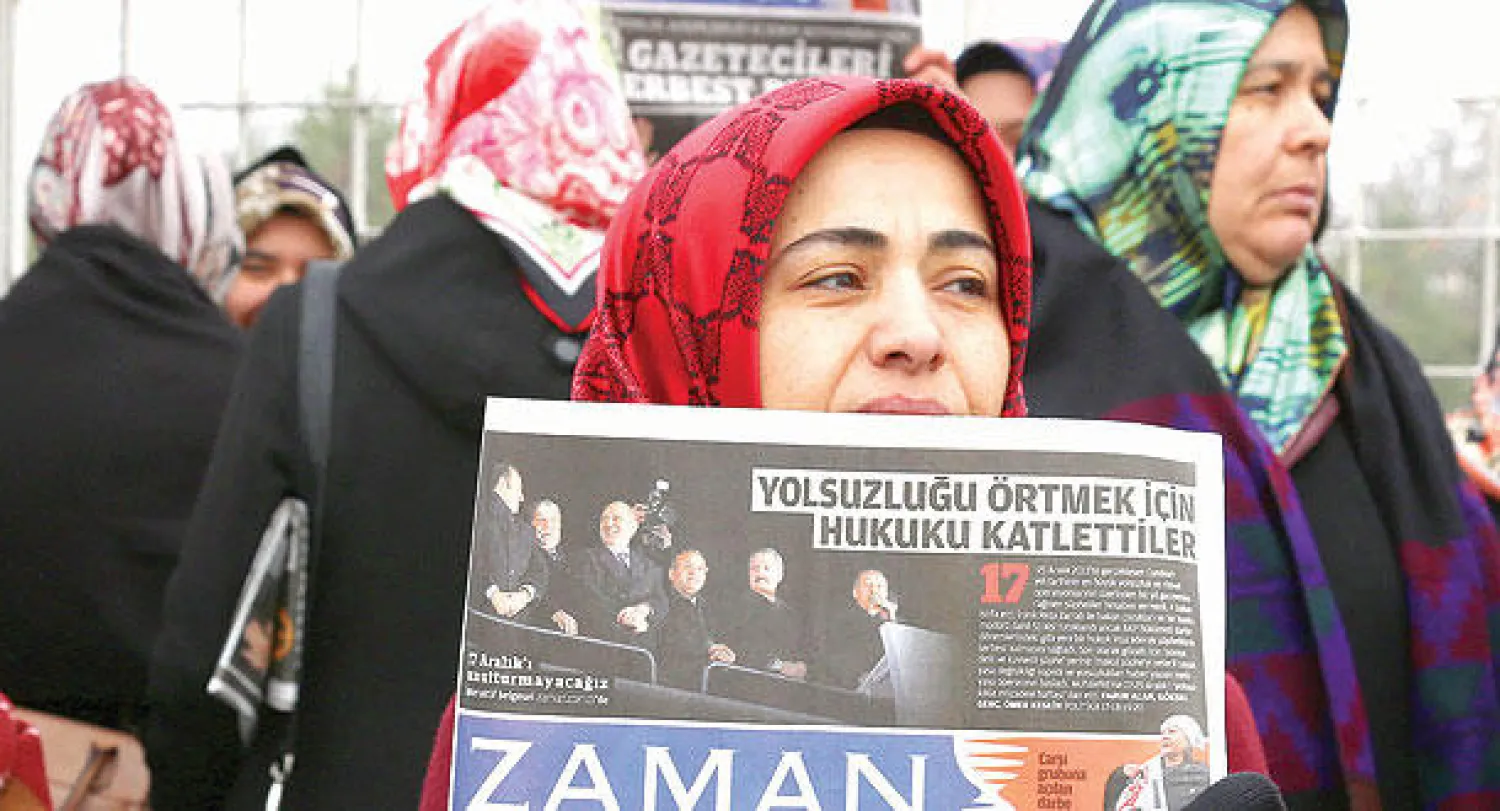متظاهرة تحمل نسخة من صحيفة «زمان» خلال مظاهرة في أنقرة أمس ضد اعتقال رئيس تحرير  لصحيفة وصحافيين آخرين (أ.ب)