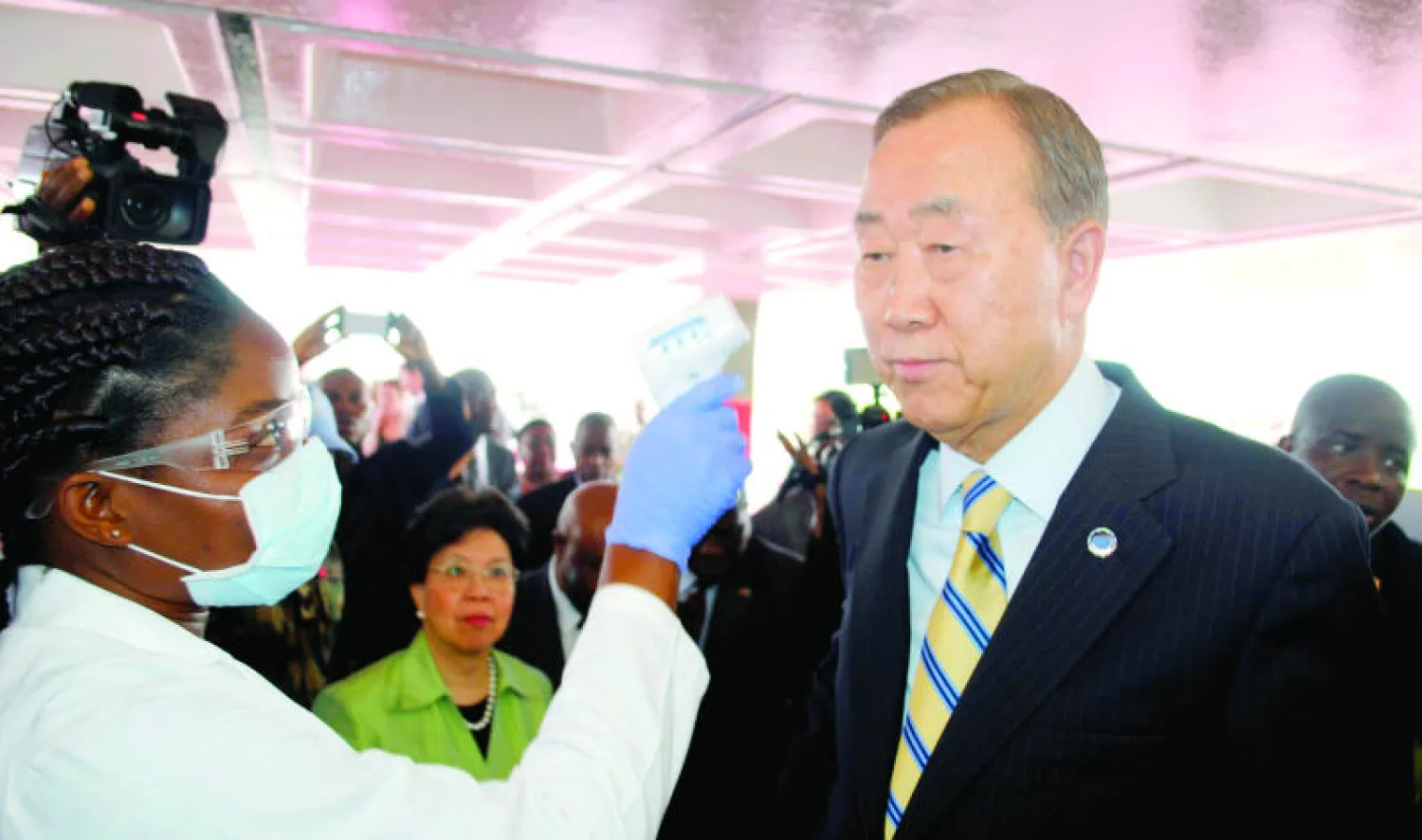 بان كي مون يخضع لقياس درجة حرارته أثناء وصوله إلى «مطار روبرتس الدولي» بالعاصمة الليبيرية أمس (رويترز)