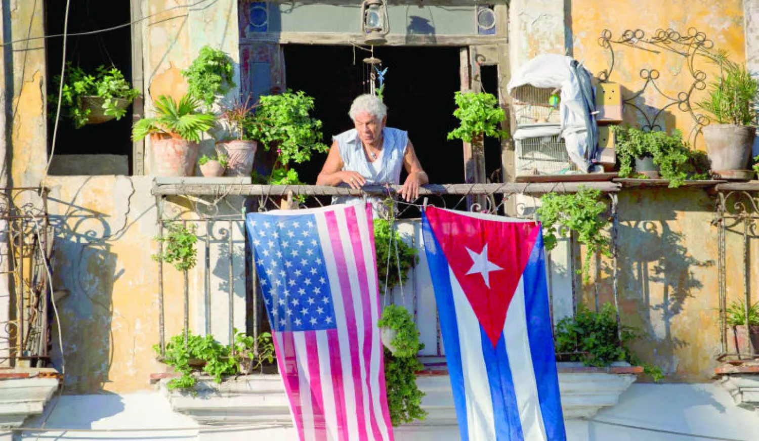 كوبية تطل من شرفة منزلها في العاصمة هافانا حيث علقت العلمين الكوبي والأميركي أمس (أ.ب)