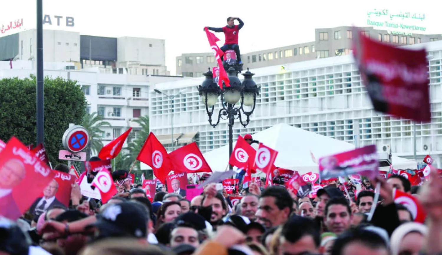 تونسي يعتلي عمود انارة وسط تجمع لمؤيدي الباجي قائد السبسي في آخر حملة دعائية في تونس أمس (أ.ف.ب)
