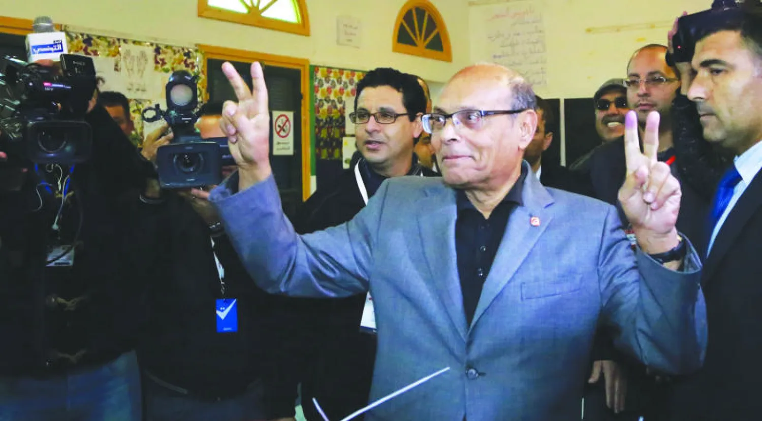 المرشح في انتخابات الرئاسة التونسية المنصف المرزوقي يلوح بإشارة النصر بعد إدلائه بصوته في سوسة أمس (إ.ب.أ)