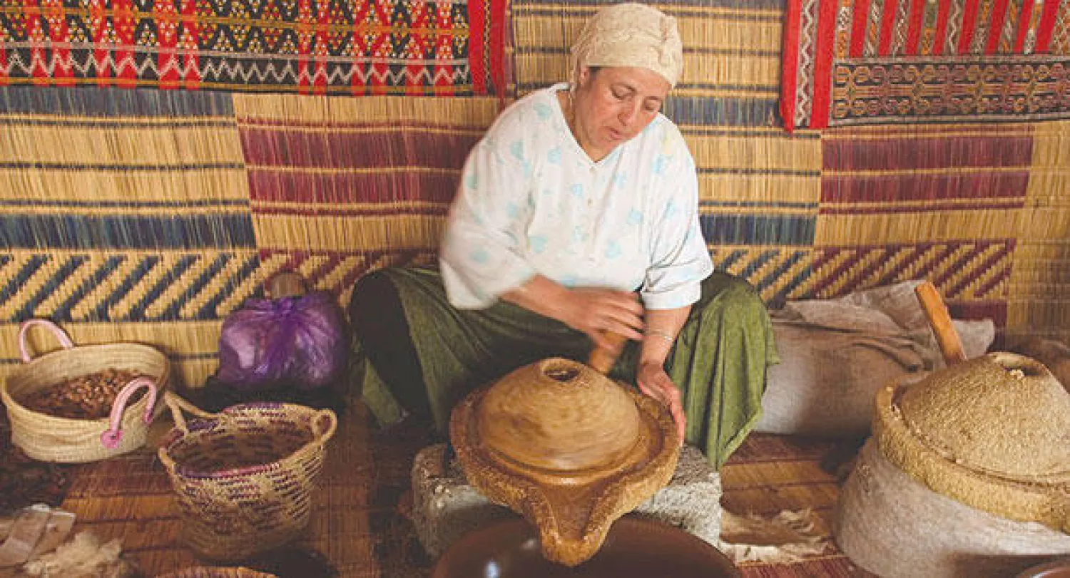 مغربية تطحن حبات «أركان» برحى يدوية قبل أن تؤخذ العجينة المطحونة  وتُعصر باليد لاستخراج الزيت (تصوير: رشيد بنداود)